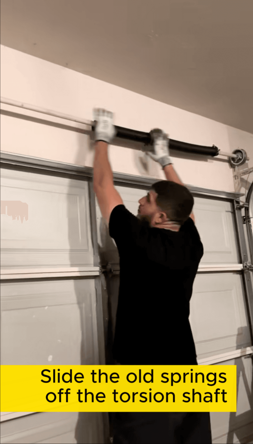 Open Sesame Garages technician sliding the old springs off the torsion shaft above the garage door
